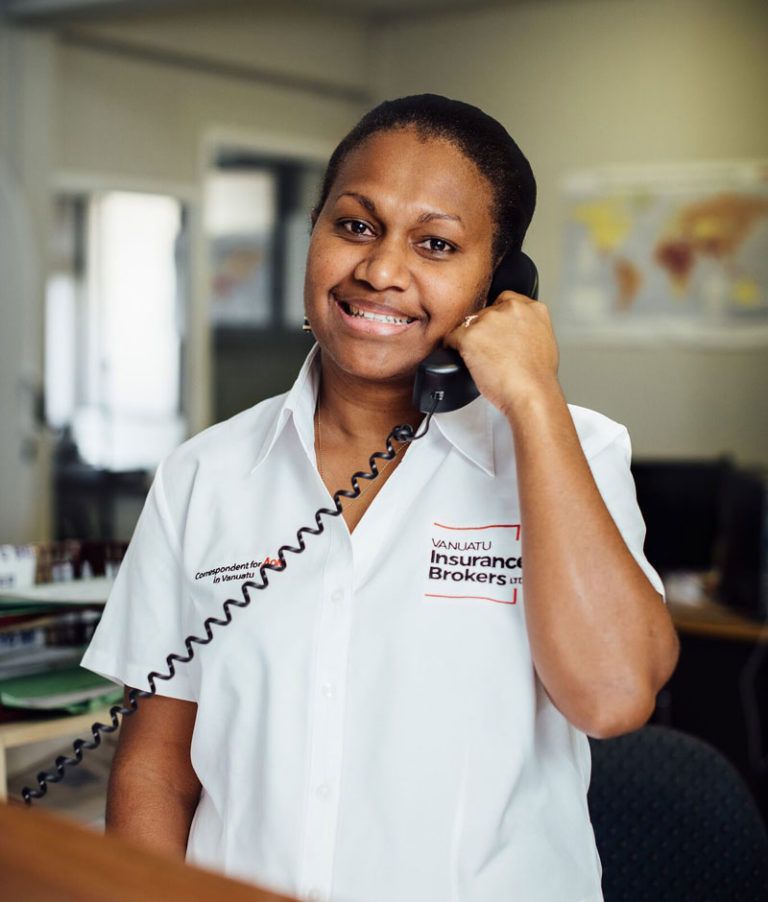 Woman in white uniform, smiling while talking on the phone, in an office setting.
