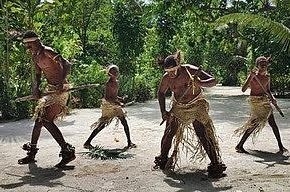 A group of men are dancing on a dirt road.
