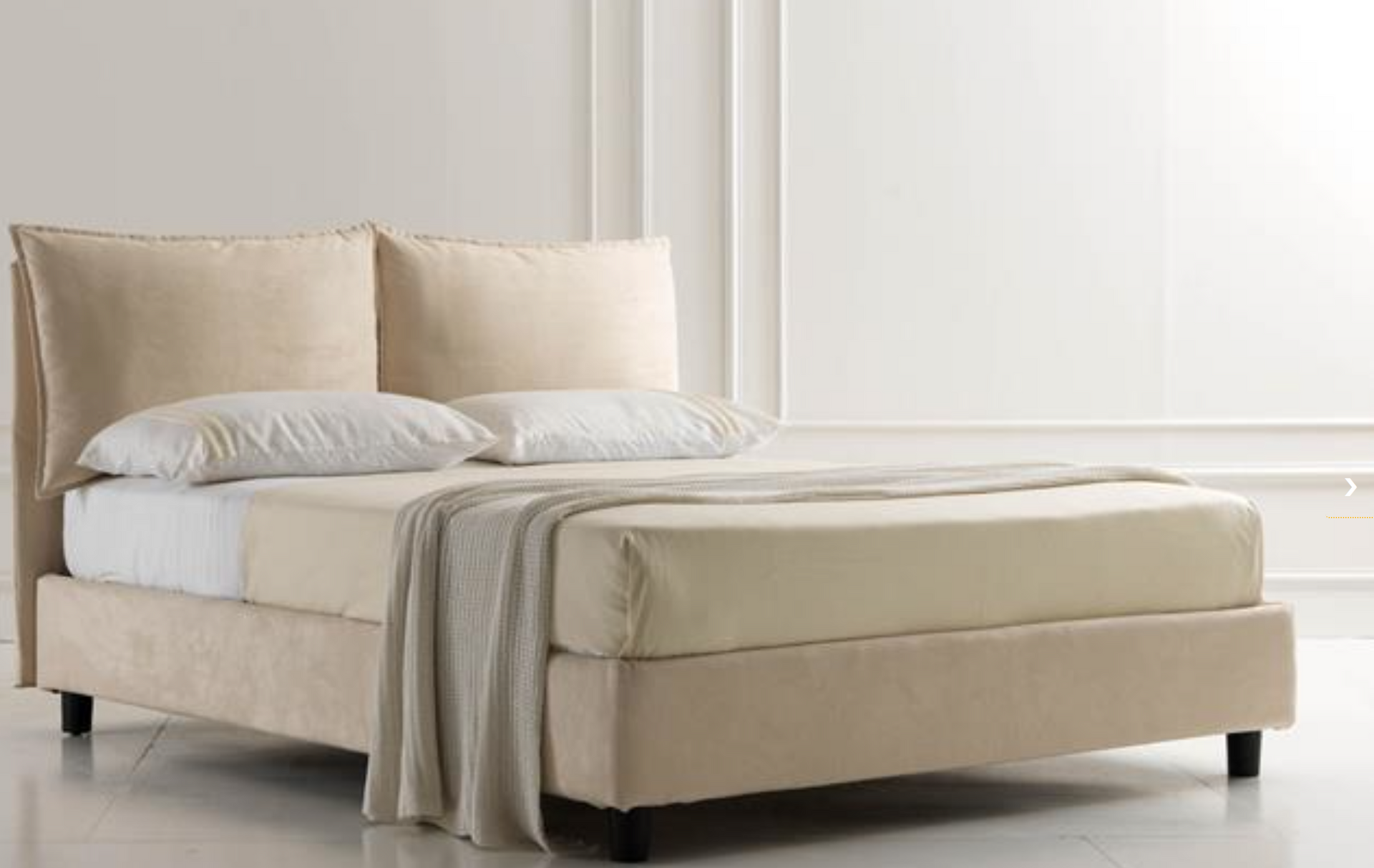 Un letto con lenzuola e cuscini bianchi in una camera da letto.