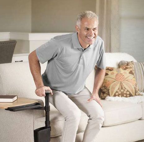 Man using a standing assist device to get up from a couch in a living room.