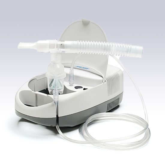 A white and grey home nebulizer machine with a connected mouthpiece, tubing, and medication cup on a white background.