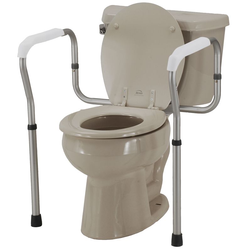 Tan toilet with a height-adjustable, silver-colored metal safety rail frame with white hand grips for stability.