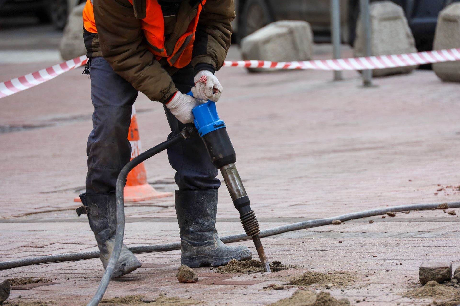 A man is using an air hammer to drill a hole in the ground.