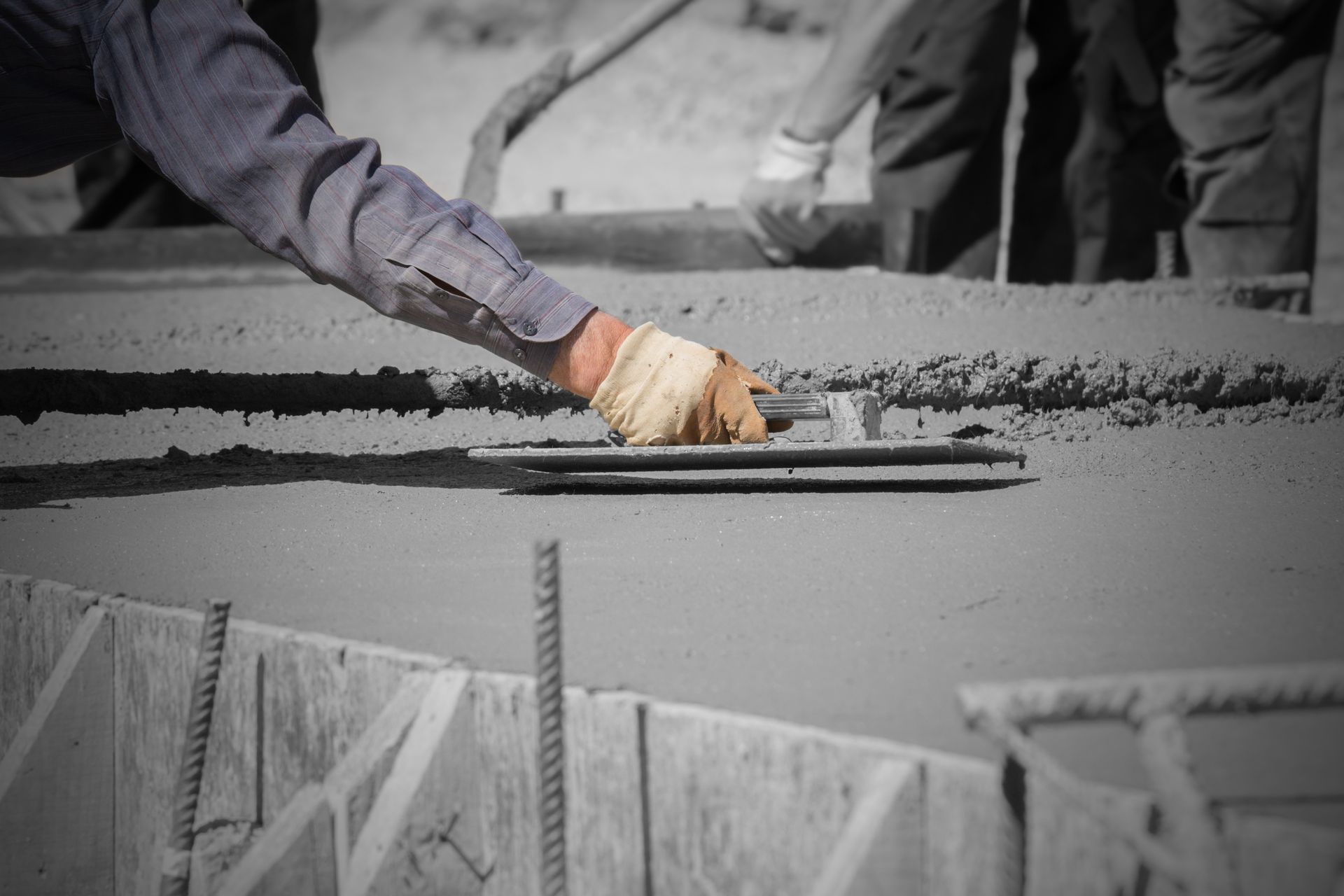 A man is using a trowel to spread concrete on a construction site.