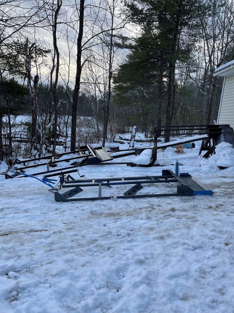 A snowmobile is sitting in the snow in front of a house.