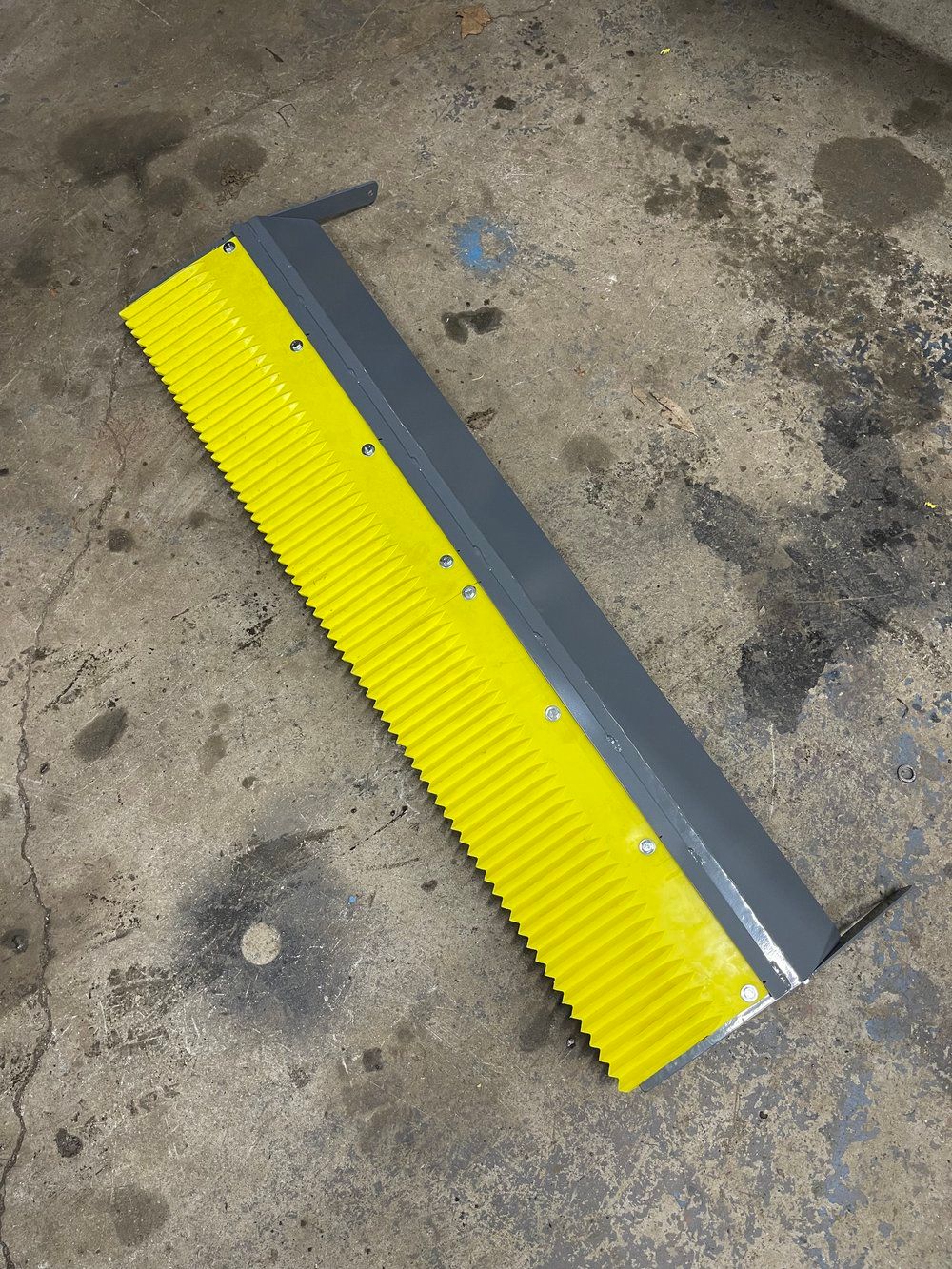 A yellow comb is sitting on a concrete surface.