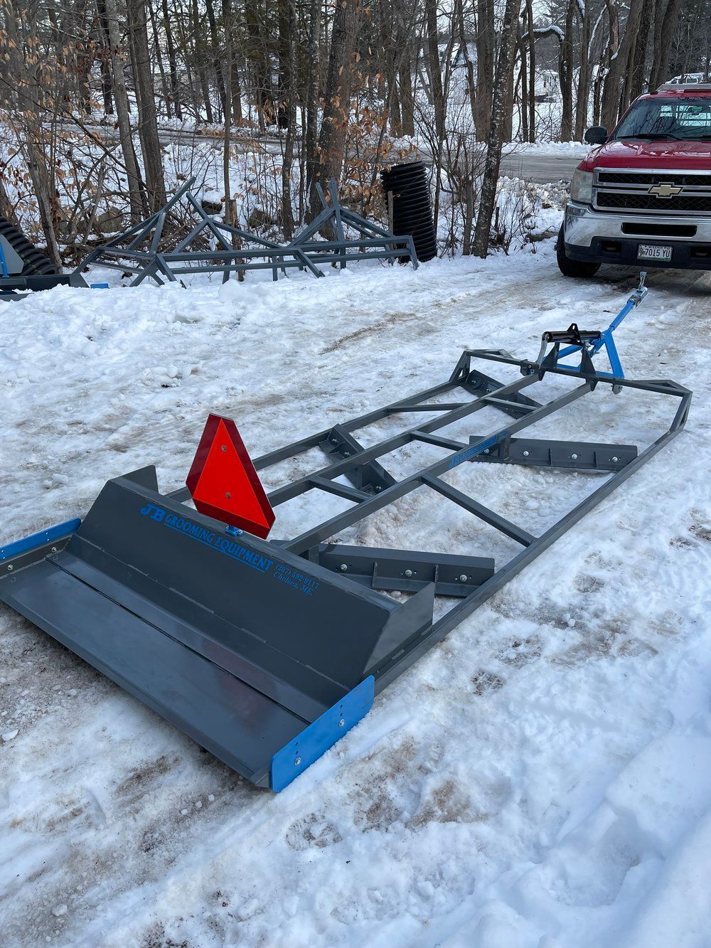 A snow plow is sitting in the snow next to a truck.