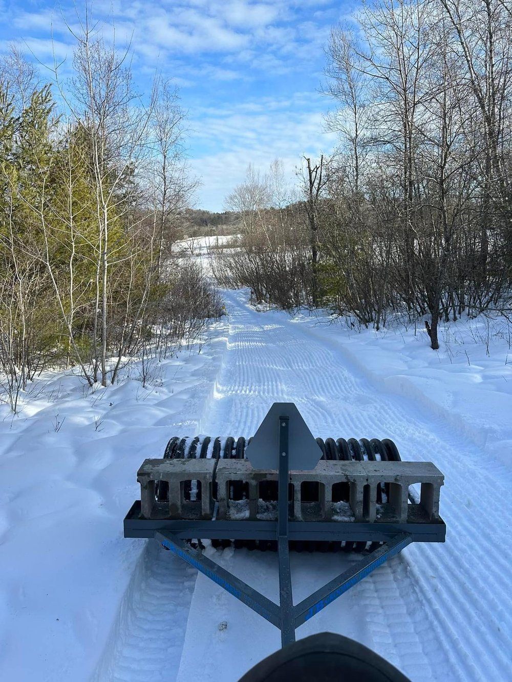 A person is riding a snowmobile down a snowy road.