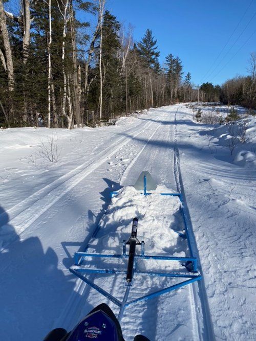 A person is riding a snowmobile down a snowy road.