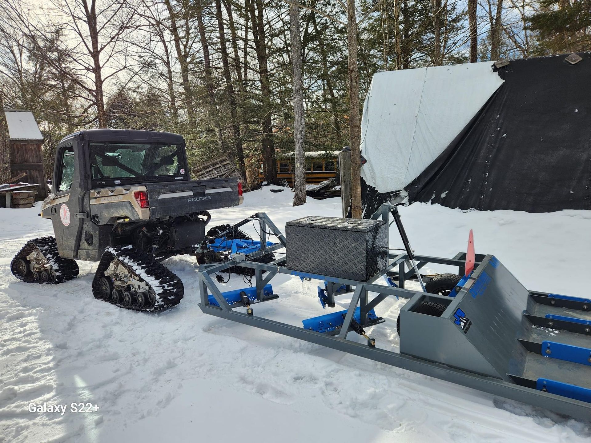 A snowmobile is parked in the snow next to a tent.