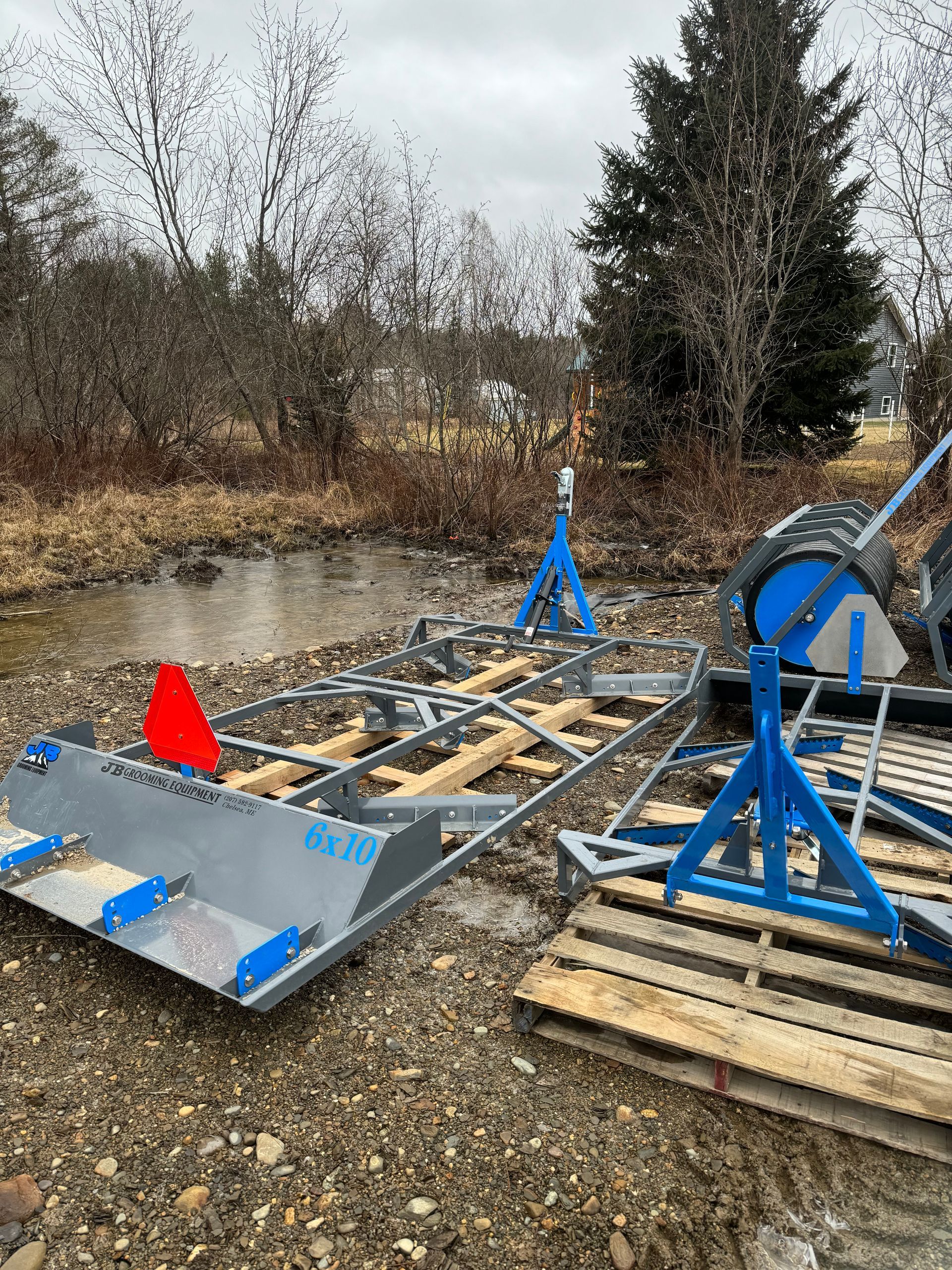 A snowmobile is sitting on top of a wooden pallet next to a body of water.