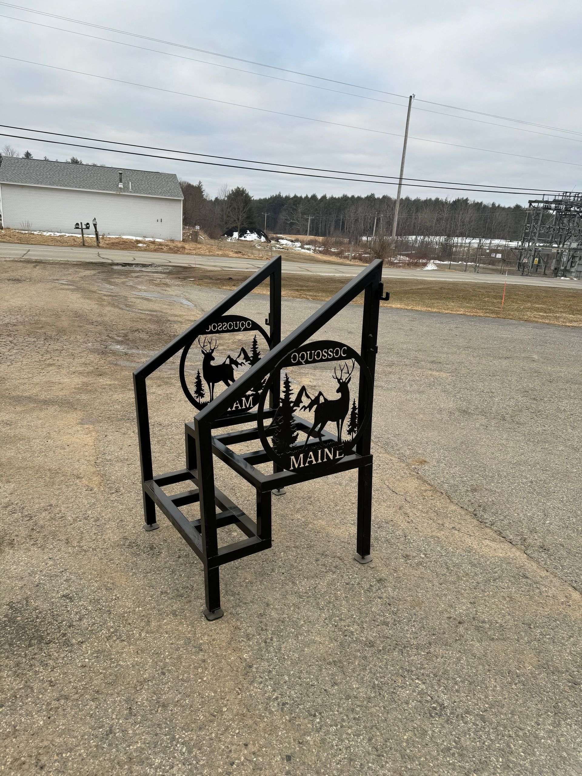 A metal staircase with a deer on it is sitting on the ground.