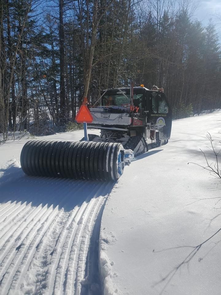 A truck is driving down a snow covered road