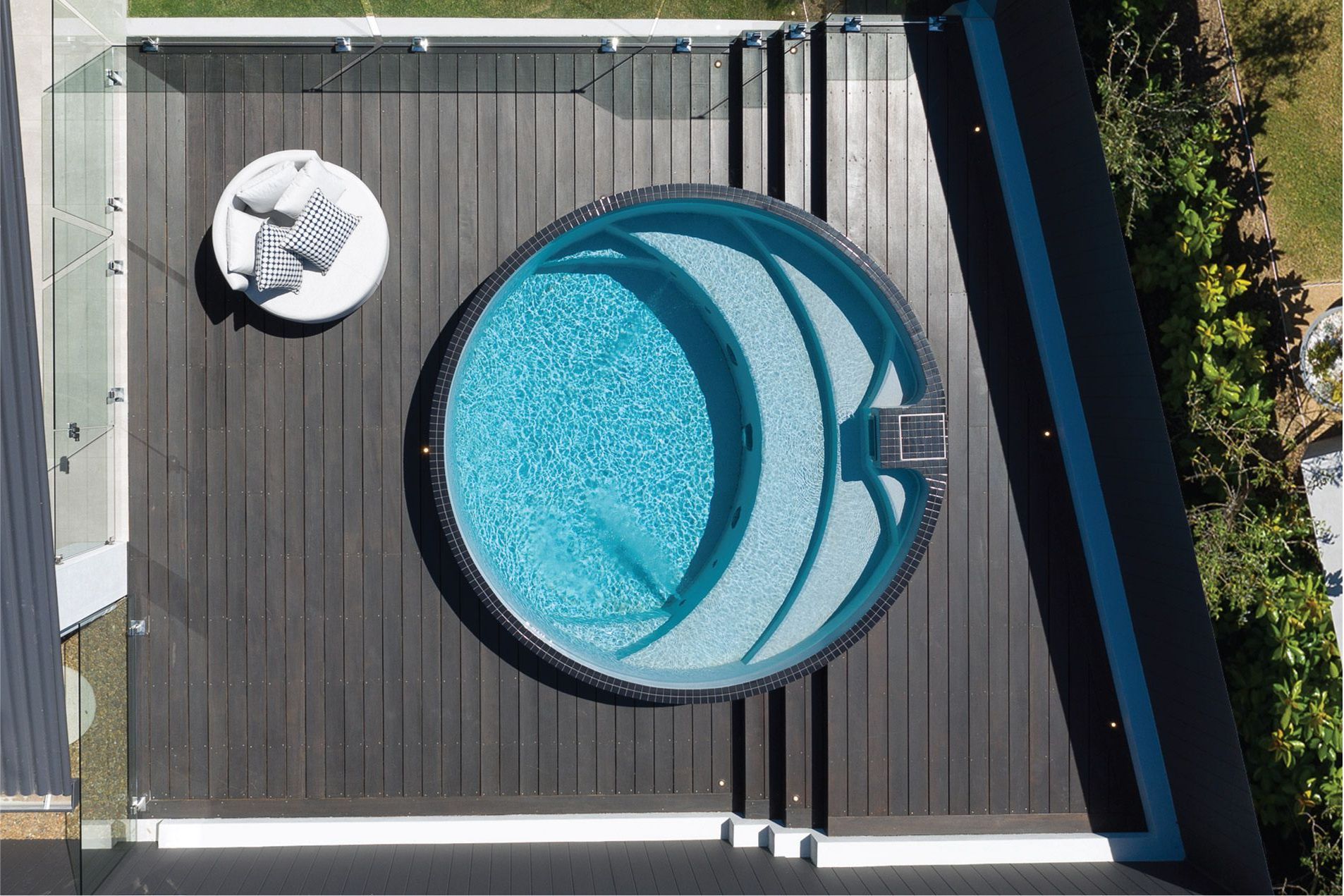 A truck with a crane attached to it is installing a precast swimming pool.