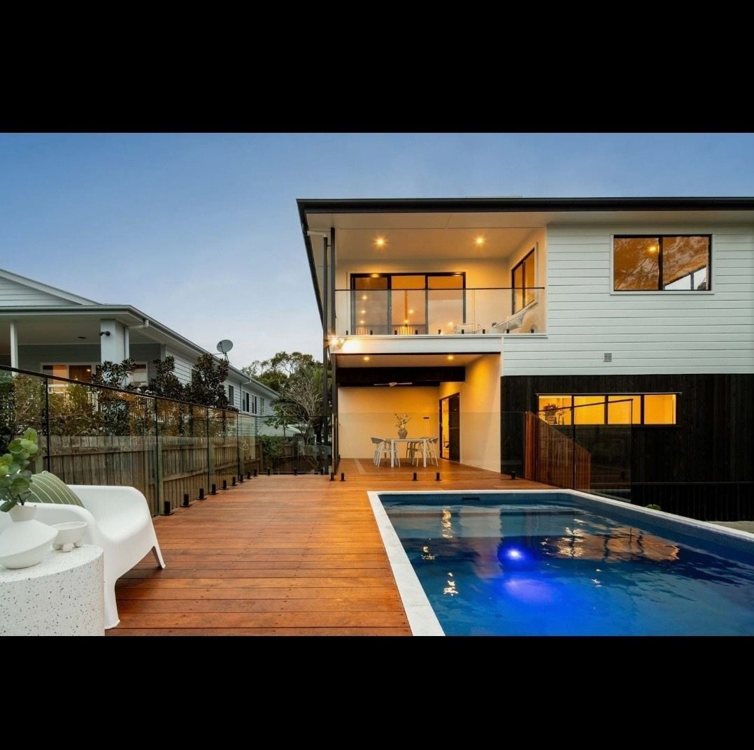 A yellow crane is lifting a Plungie pool in front of a house