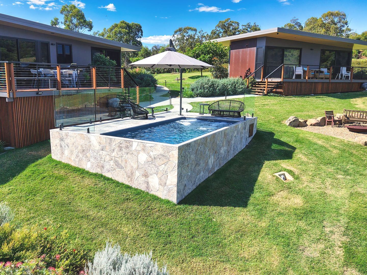 There is a large swimming pool in the middle of a lush green field.