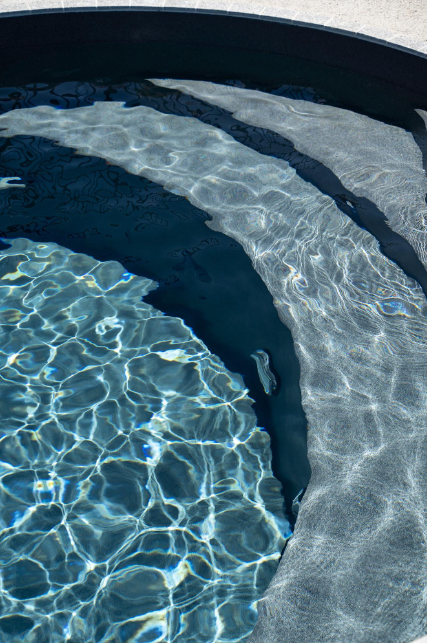A close up of a swimming pool with blue water and stairs.