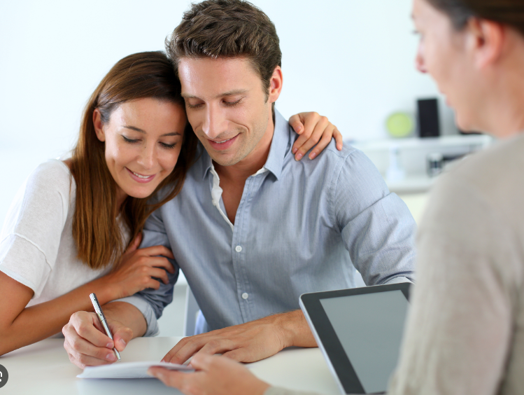 A man and a woman are sitting at a table signing a document.