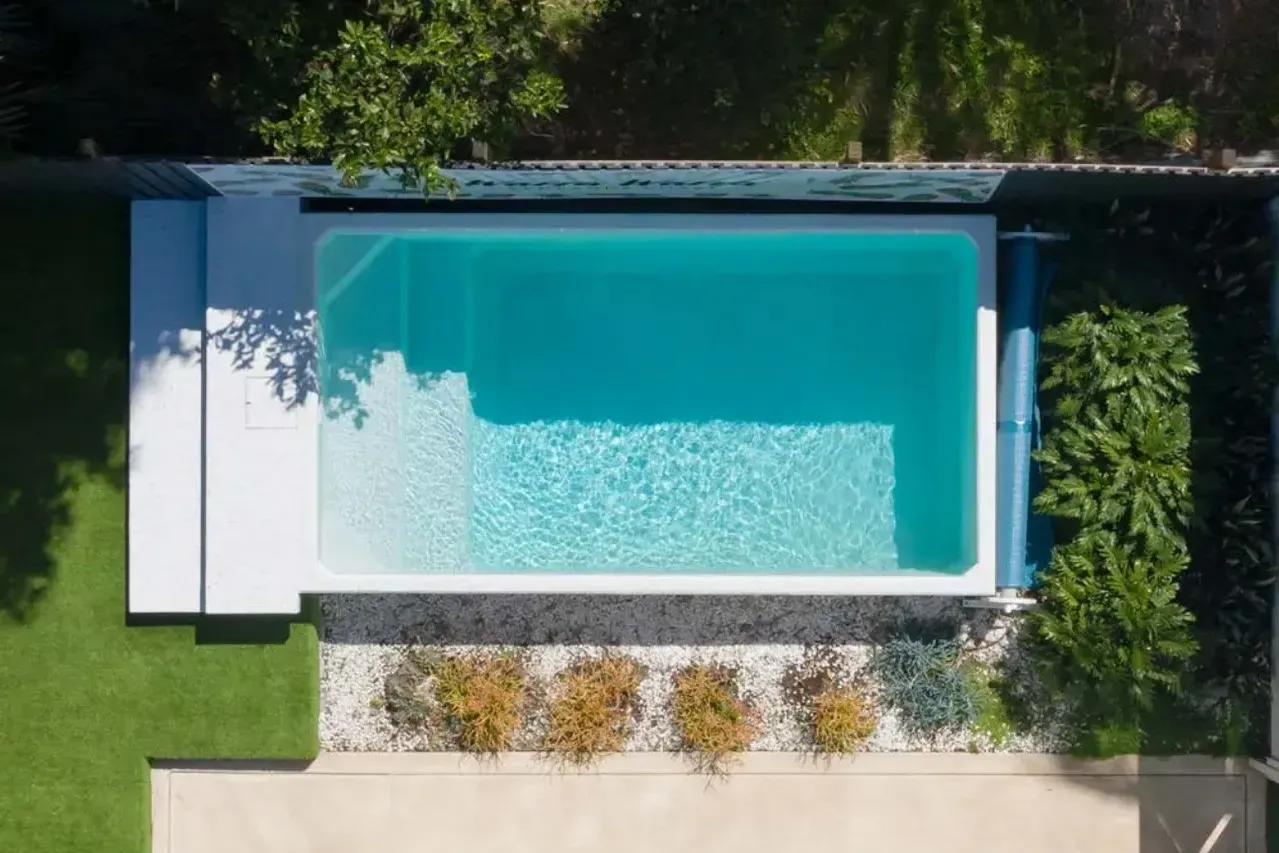 An aerial view of a Plungie Original swimming pool in a backyard surrounded by trees.