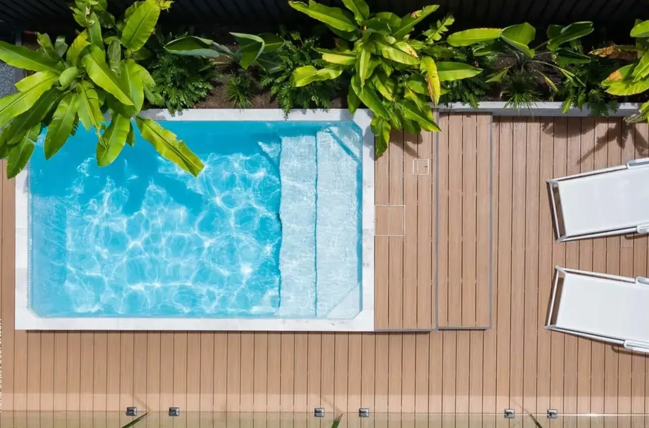 An aerial view of a Plungie Stidio swimming pool surrounded by plants and chairs.