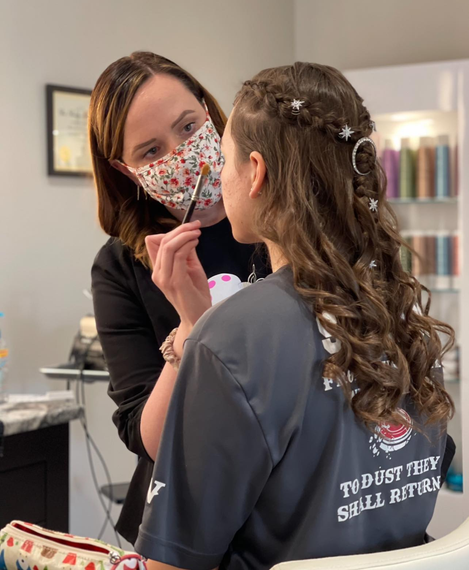 Ashley applying makeup to a customer.
