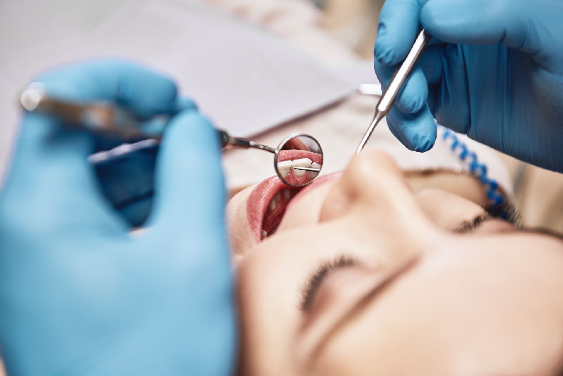 Dentist examining female patient's teeth in clinic.