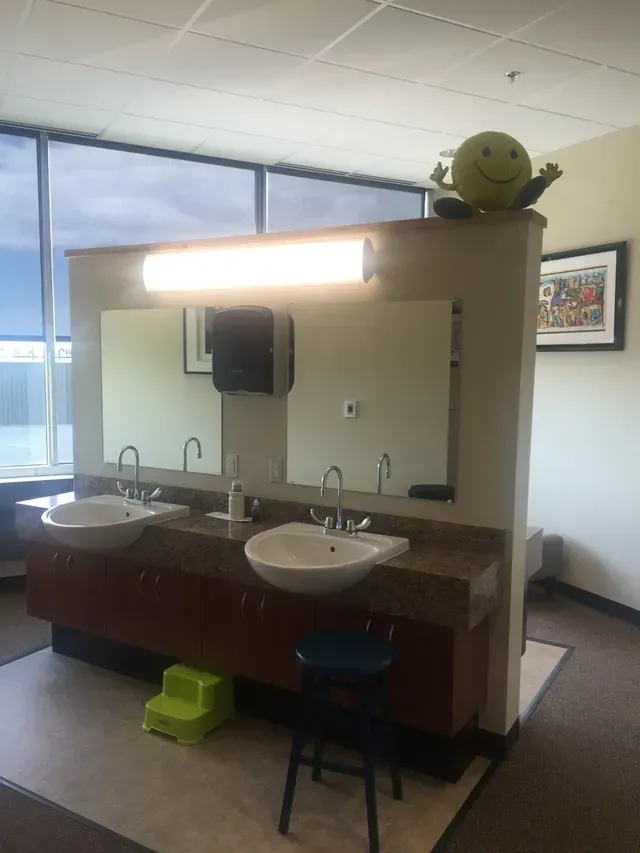 Bathroom with two sinks, mirrors, and a decorative smiley face on top.