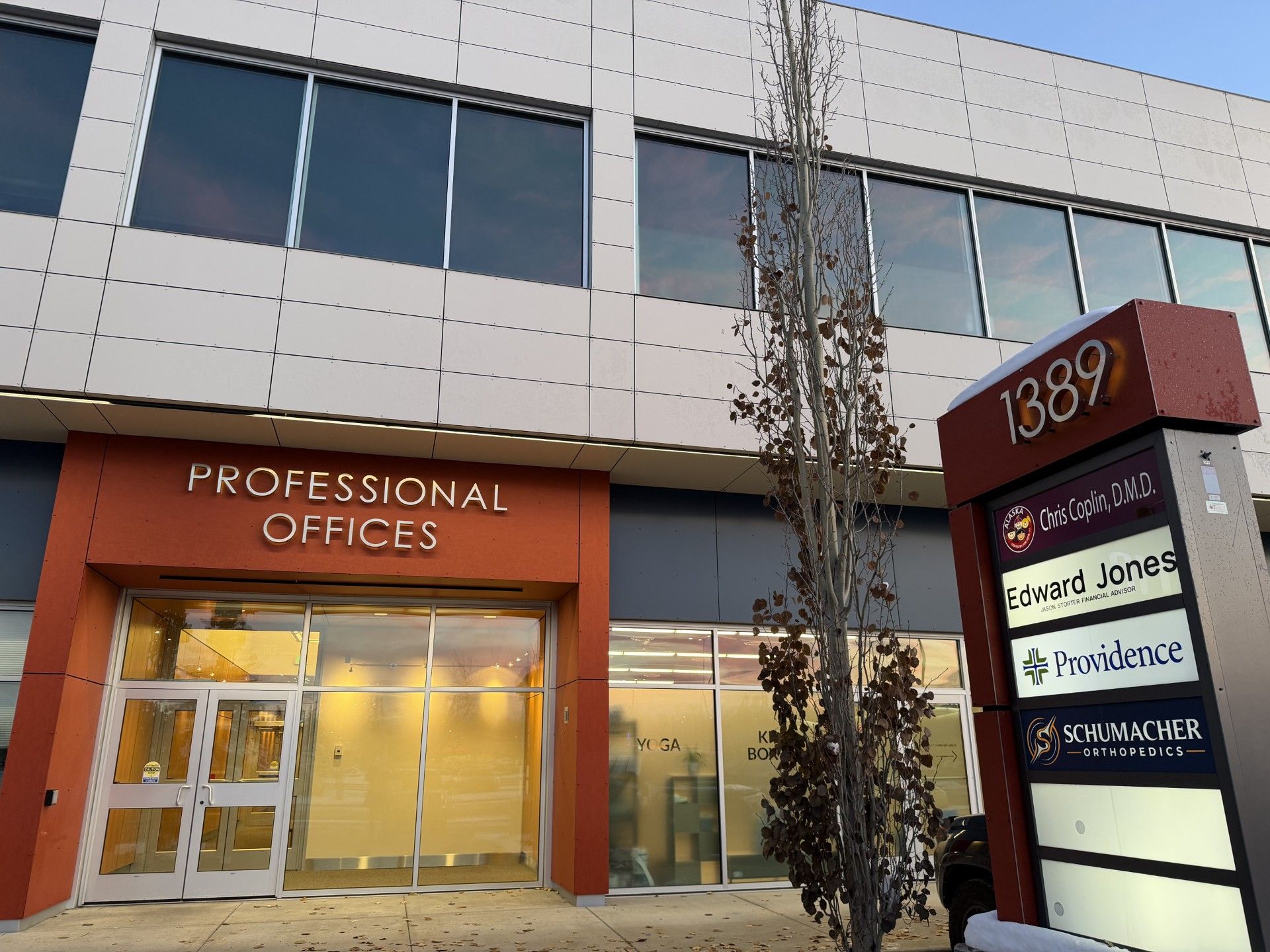 Sign for businesses, 1389, with parking lot and mountain backdrop.