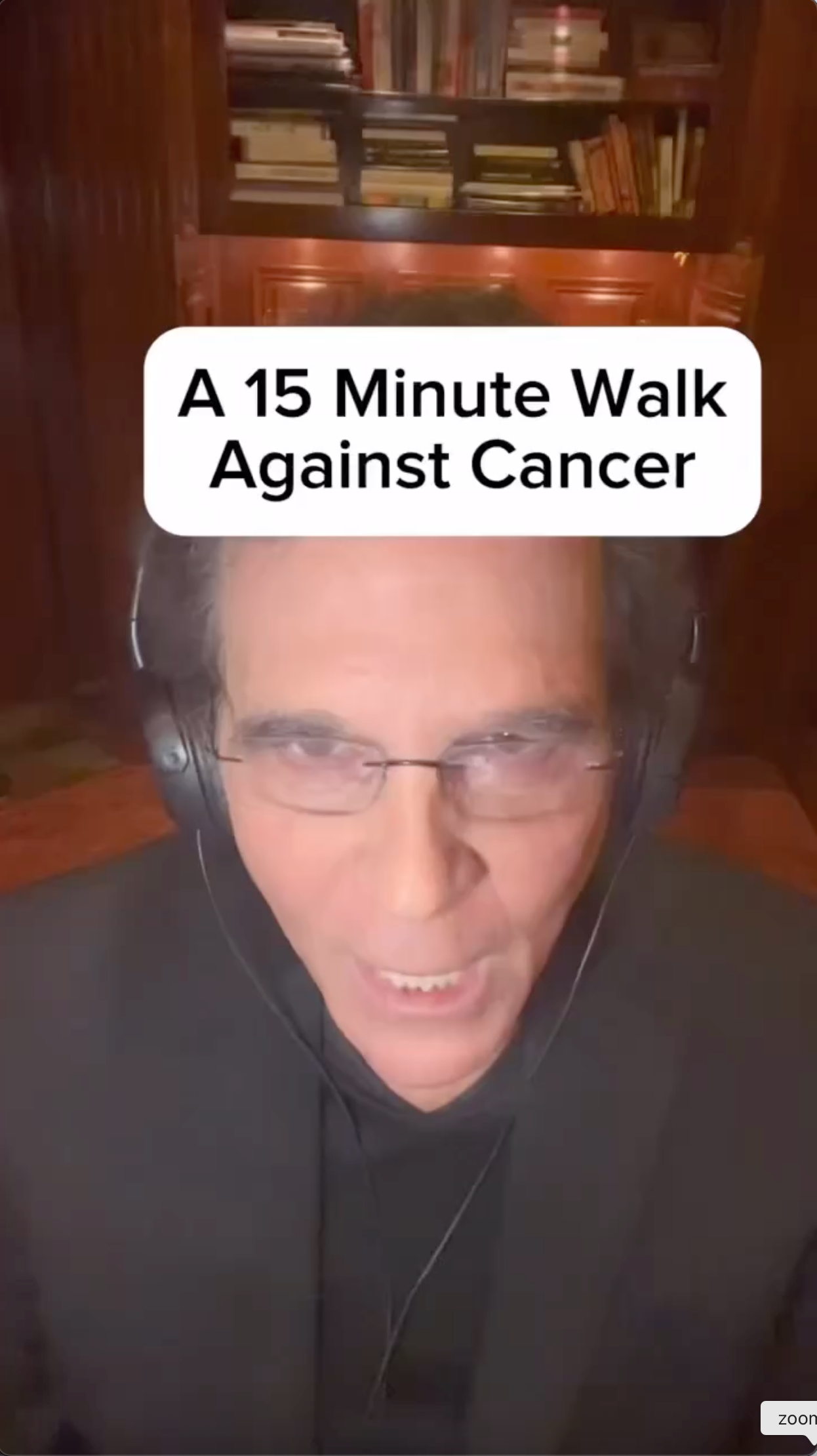 A man wearing headphones and glasses is talking about a 15-minute walk against cancer.