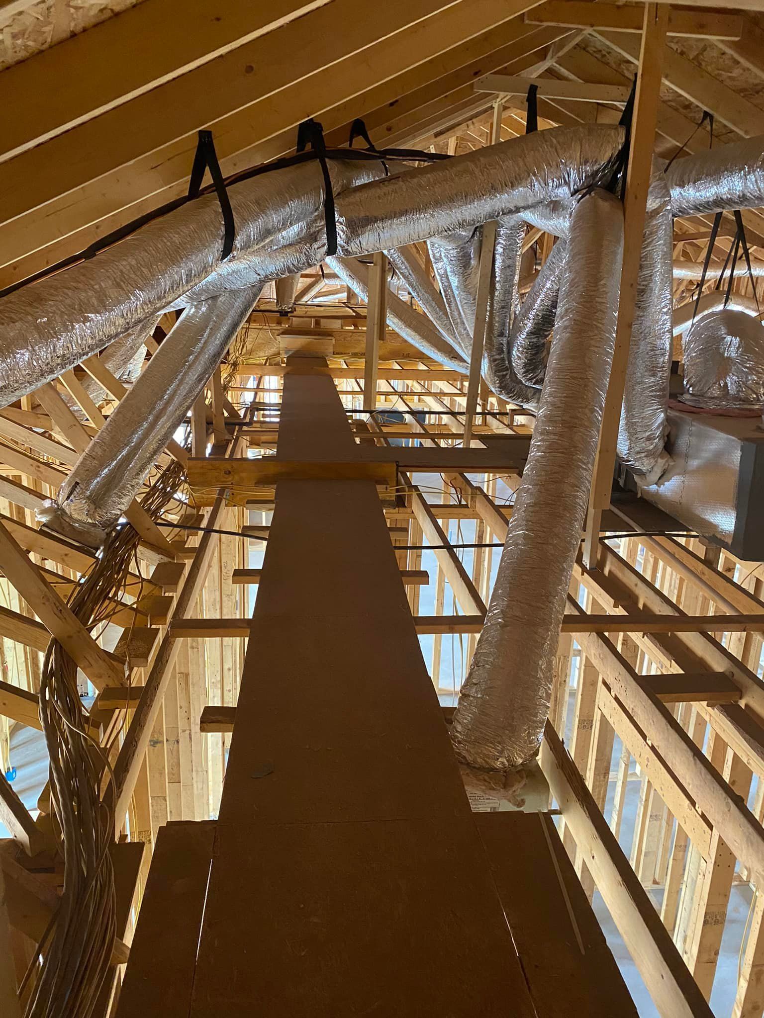 Wooden attic framing with HVAC ductwork; a long, central walkway.