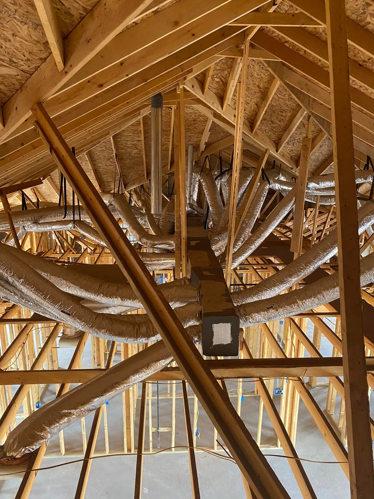 Wooden attic framing with exposed HVAC ductwork and insulation.