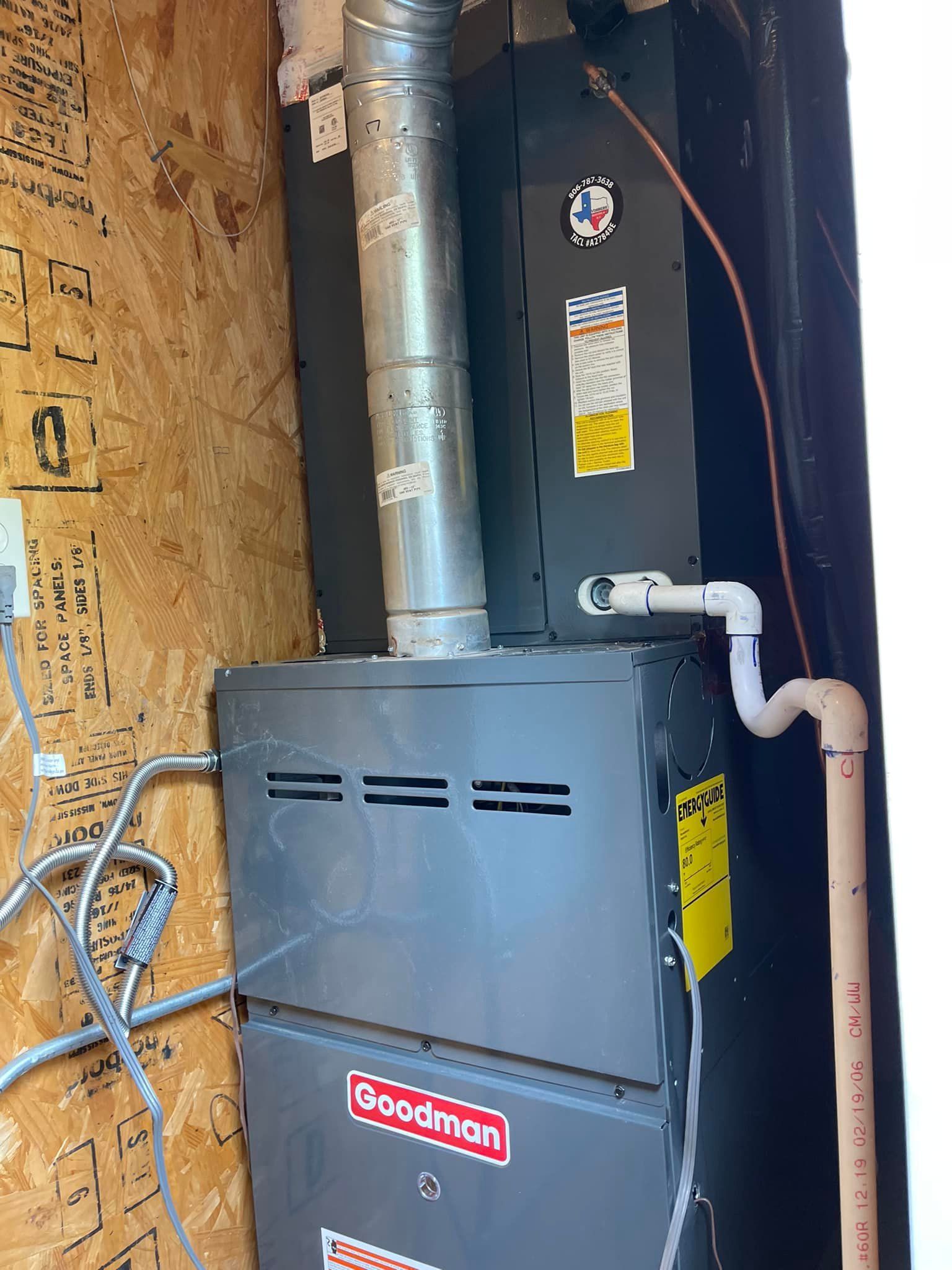 Furnace unit by Goodman with silver vent pipe, installed in a wooden enclosure.