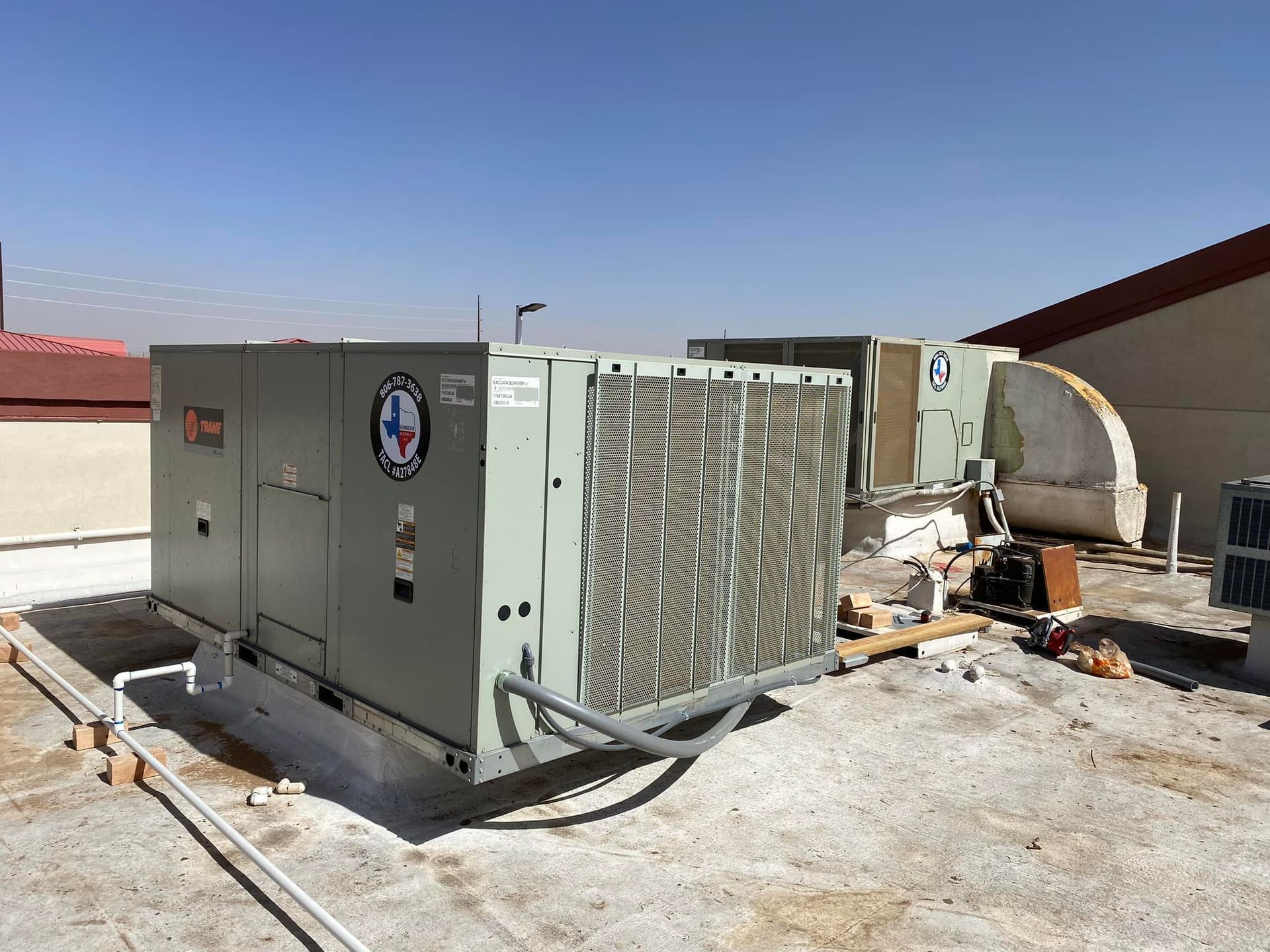 Rooftop HVAC units on a building under a clear blue sky.