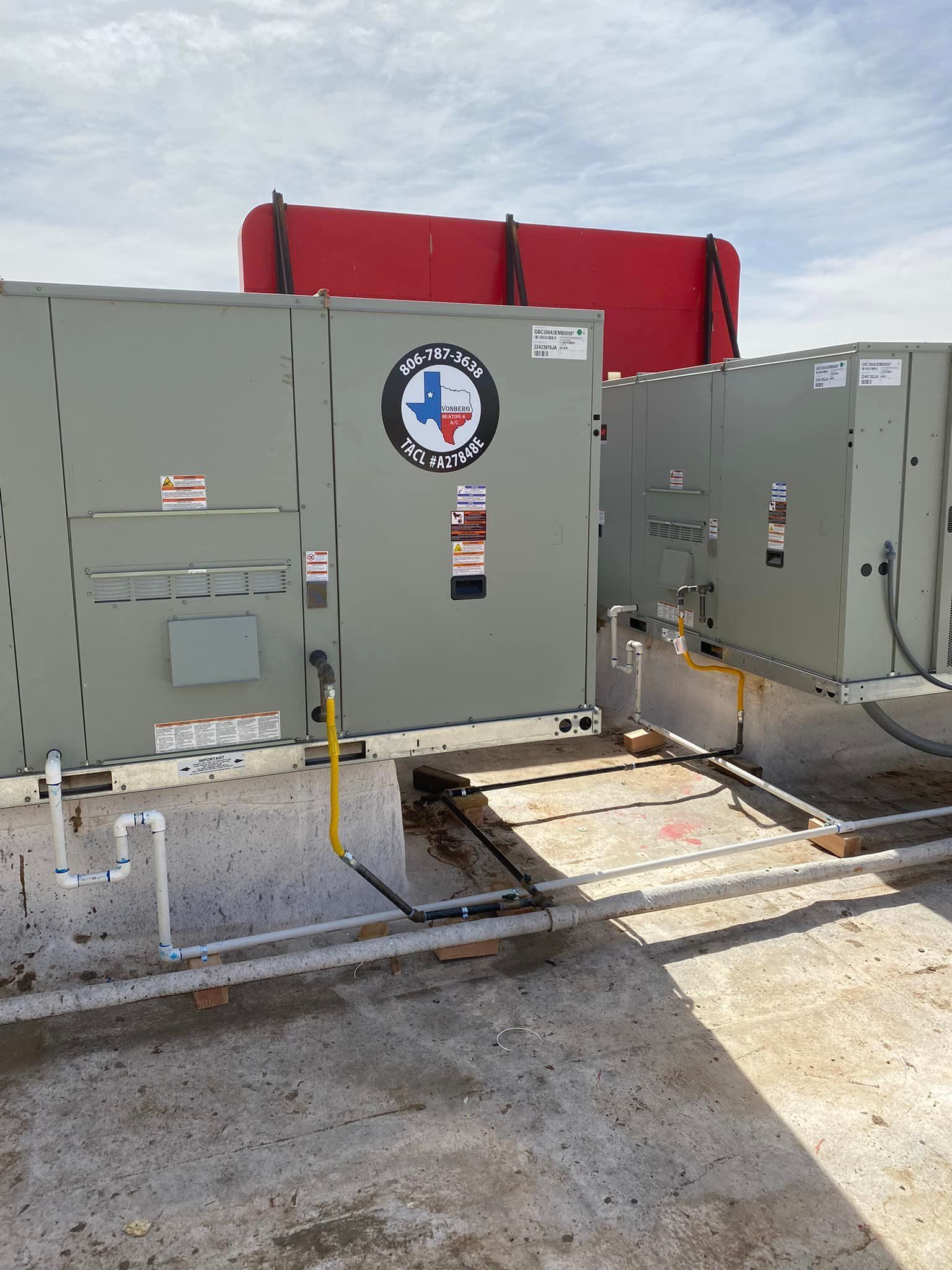 HVAC units on a rooftop with Texas logo and red tank in the background.