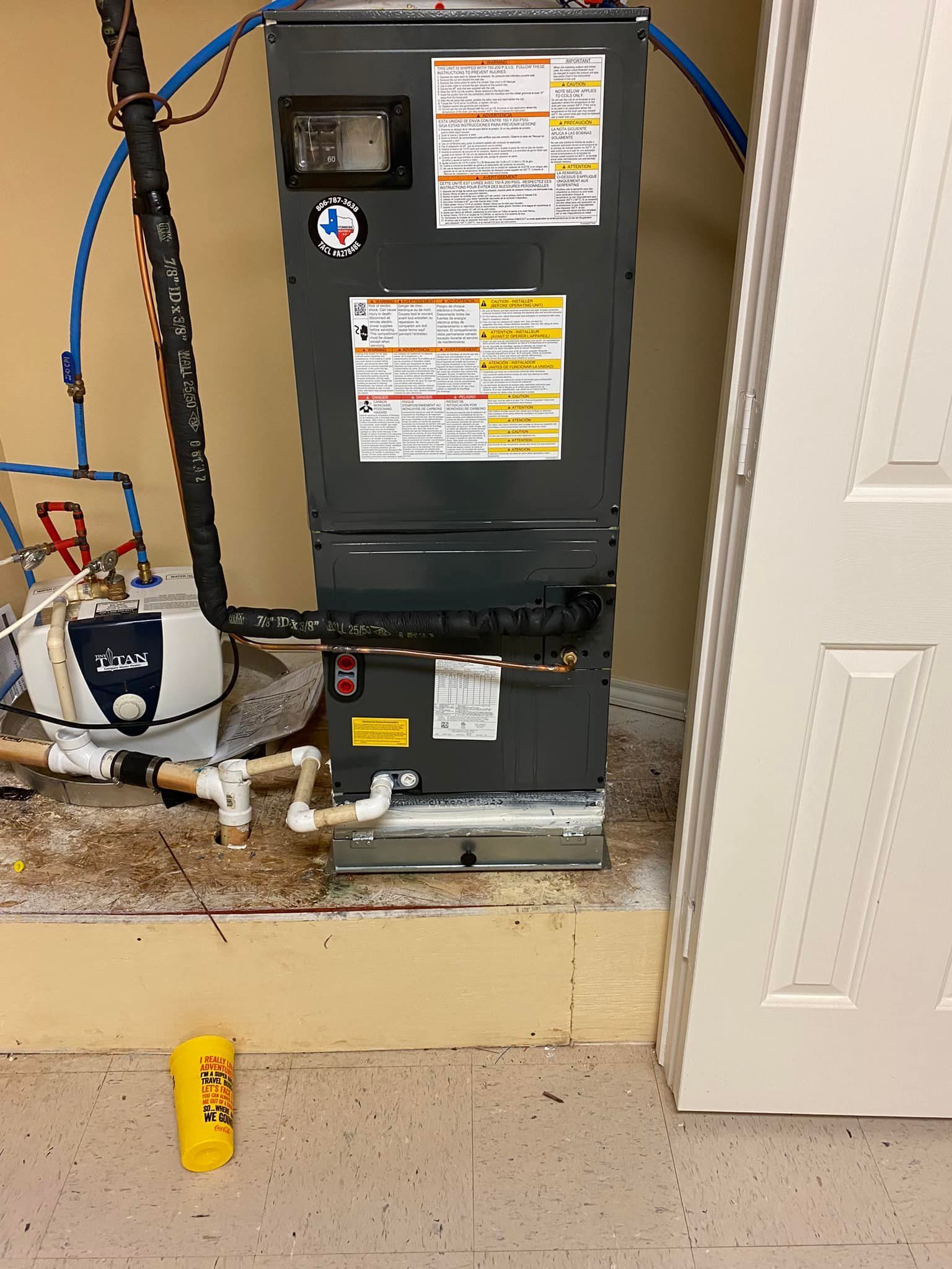 HVAC unit with connected pipes and a water heater in a utility room setting.