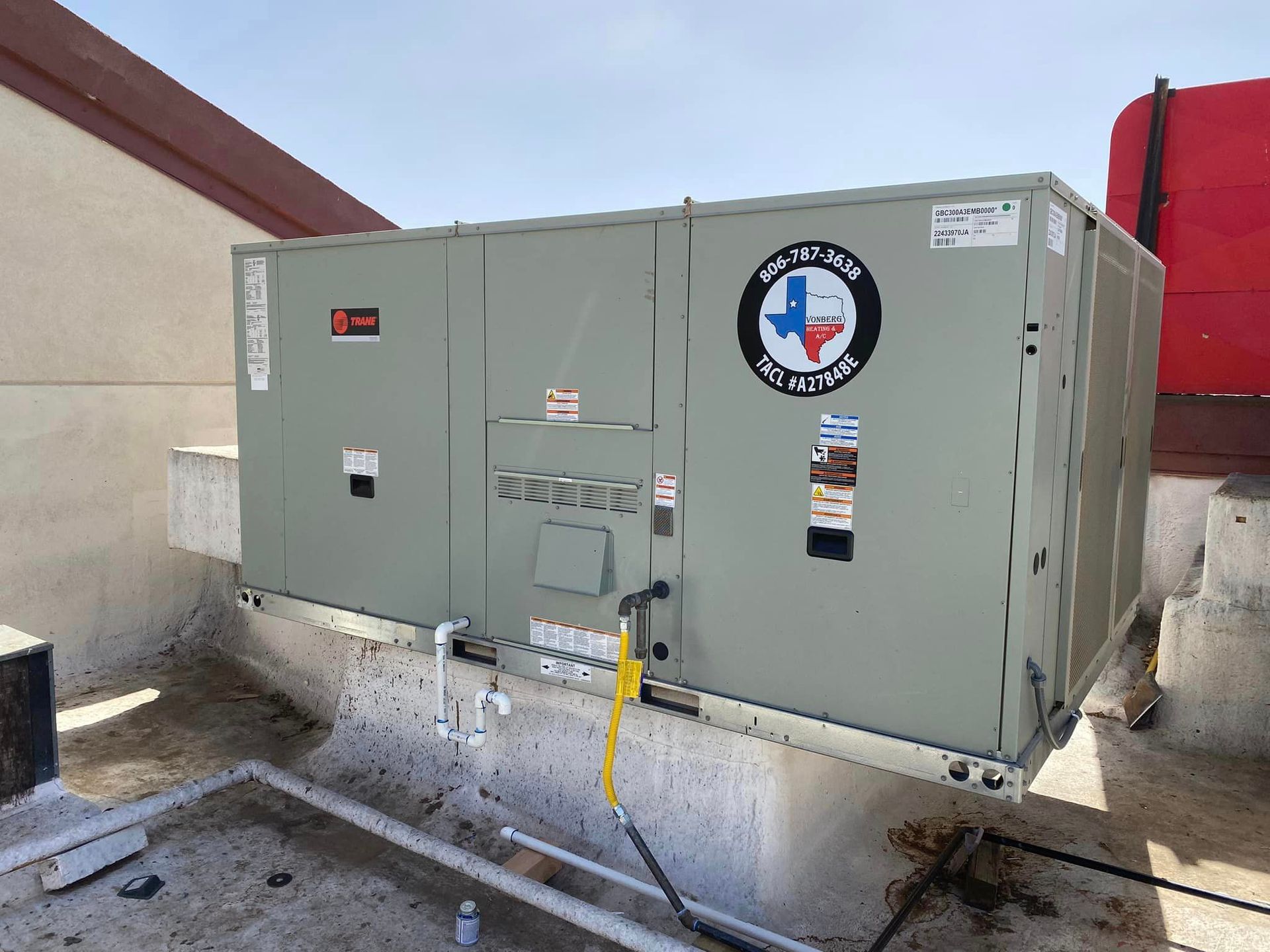 Rooftop HVAC unit with company logo; mounted on concrete, against a blue sky.