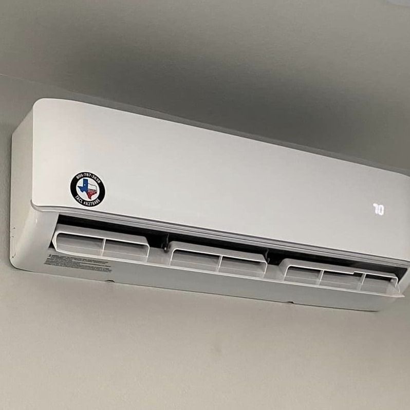 White mini-split air conditioner mounted on a light-colored wall, with a Texas flag sticker.