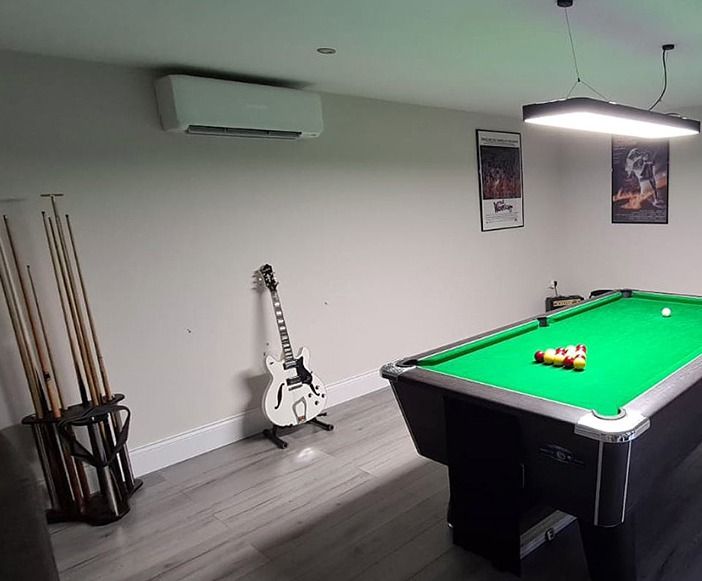 Pool table in a game room with guitar, pool cues, air conditioner, and movie posters.