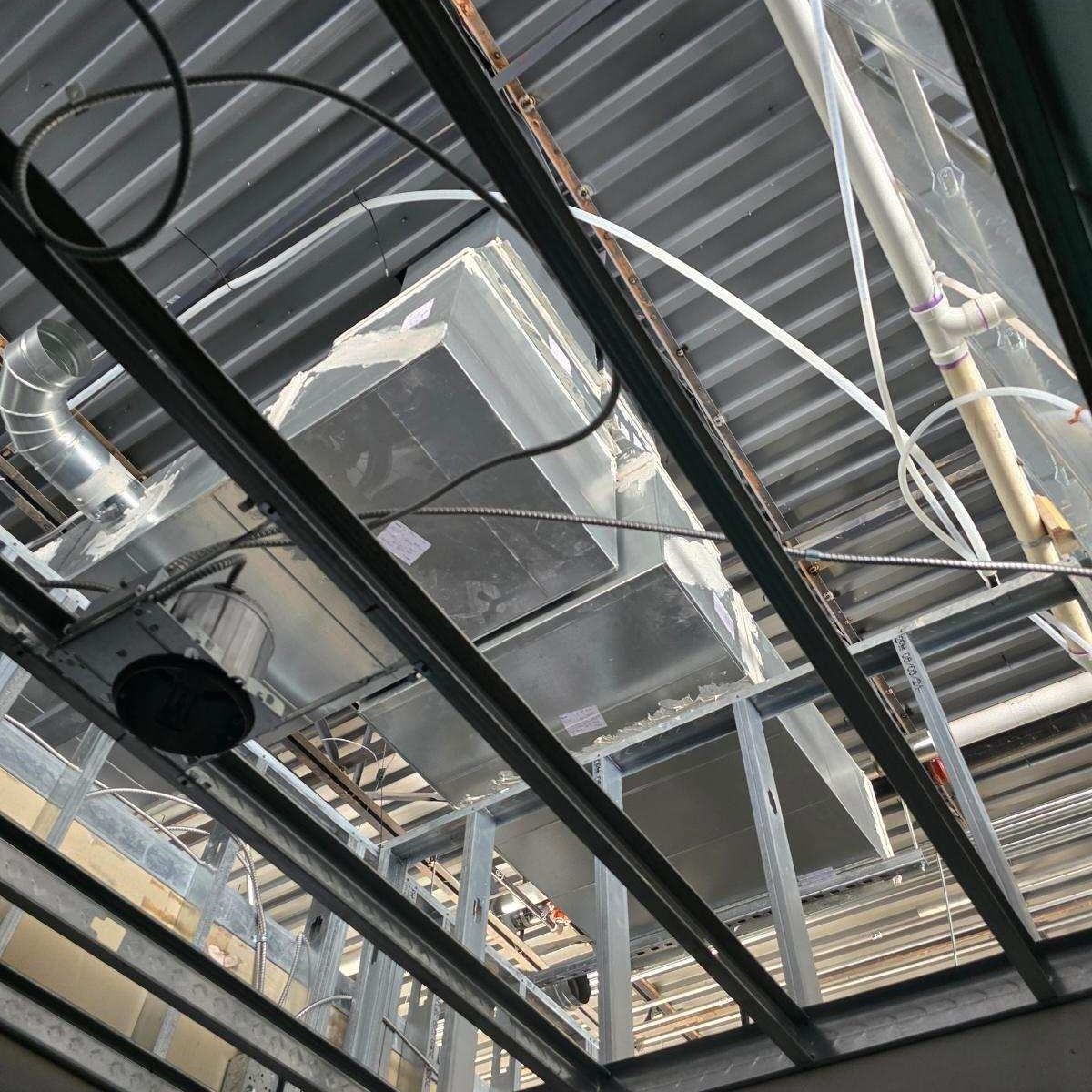 HVAC system installed on a metal ceiling frame in an unfinished building.