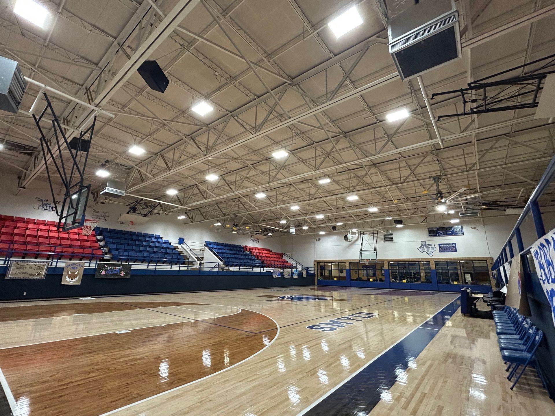 Basketball court with red and blue bleachers, overhead lighting, and the word 