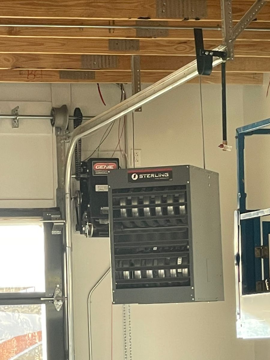 Garage heater mounted on the ceiling near a garage door, with metal and electrical components.
