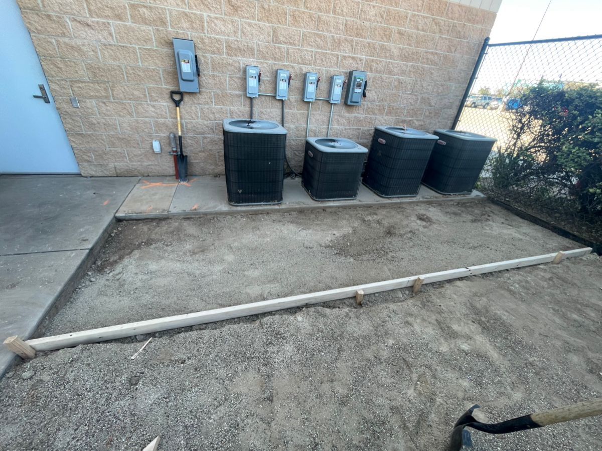 Outdoor area with AC units, electrical boxes, gravel, and a shovel.