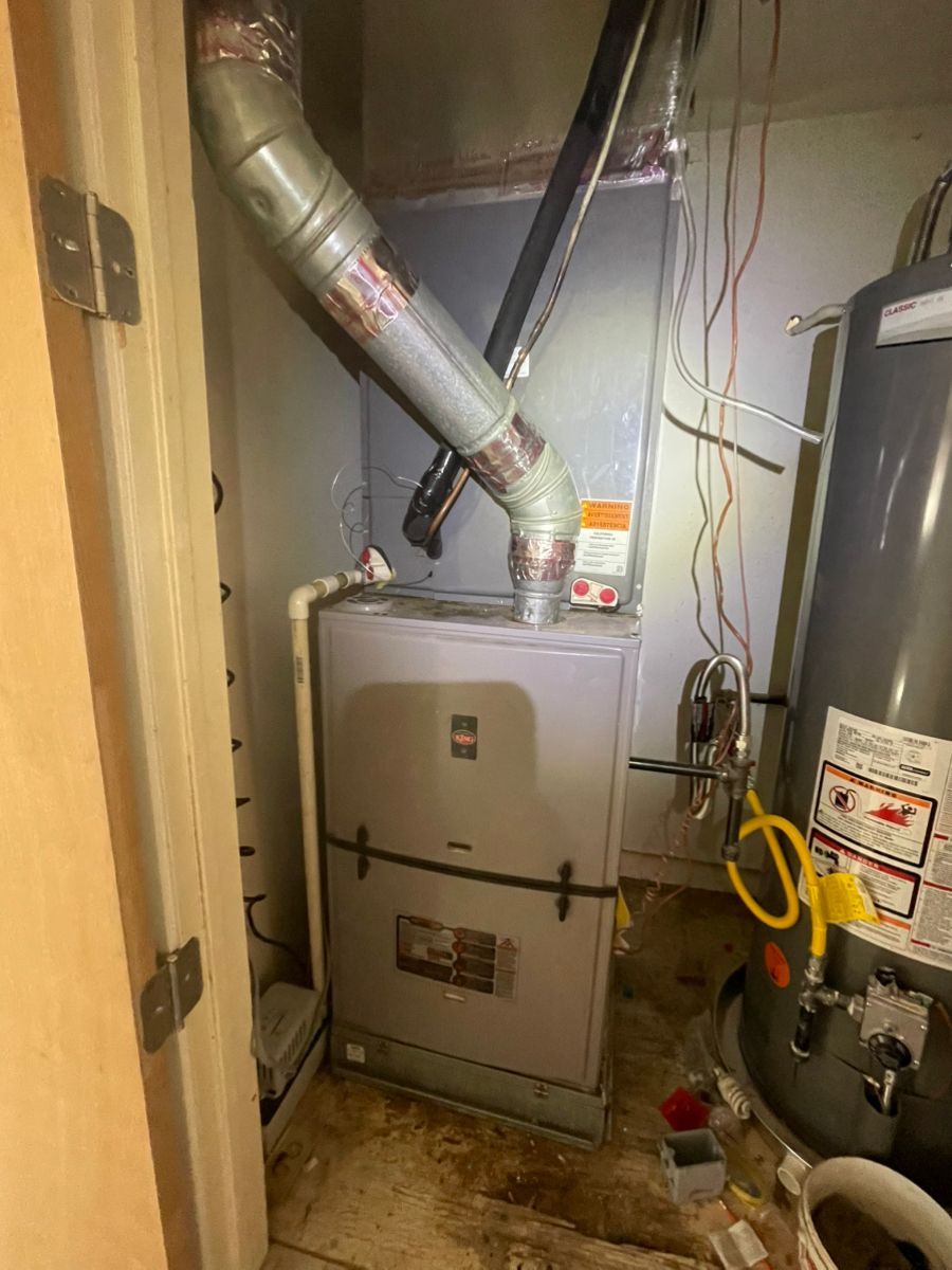Furnace in a utility closet with exhaust pipe and water heater to the right.
