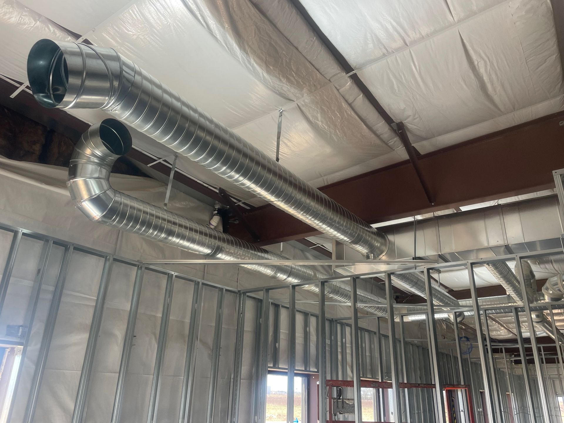 Exposed silver HVAC ducts and metal framing inside a building under construction