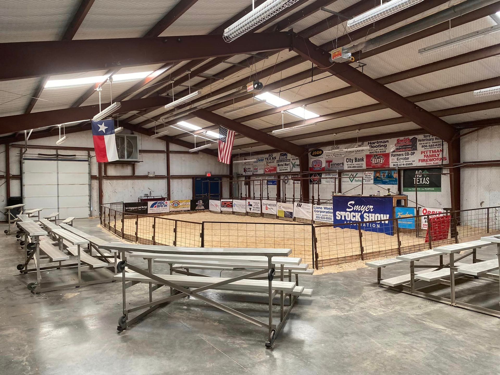 The inside of a building with a rodeo ring and bleachers.
