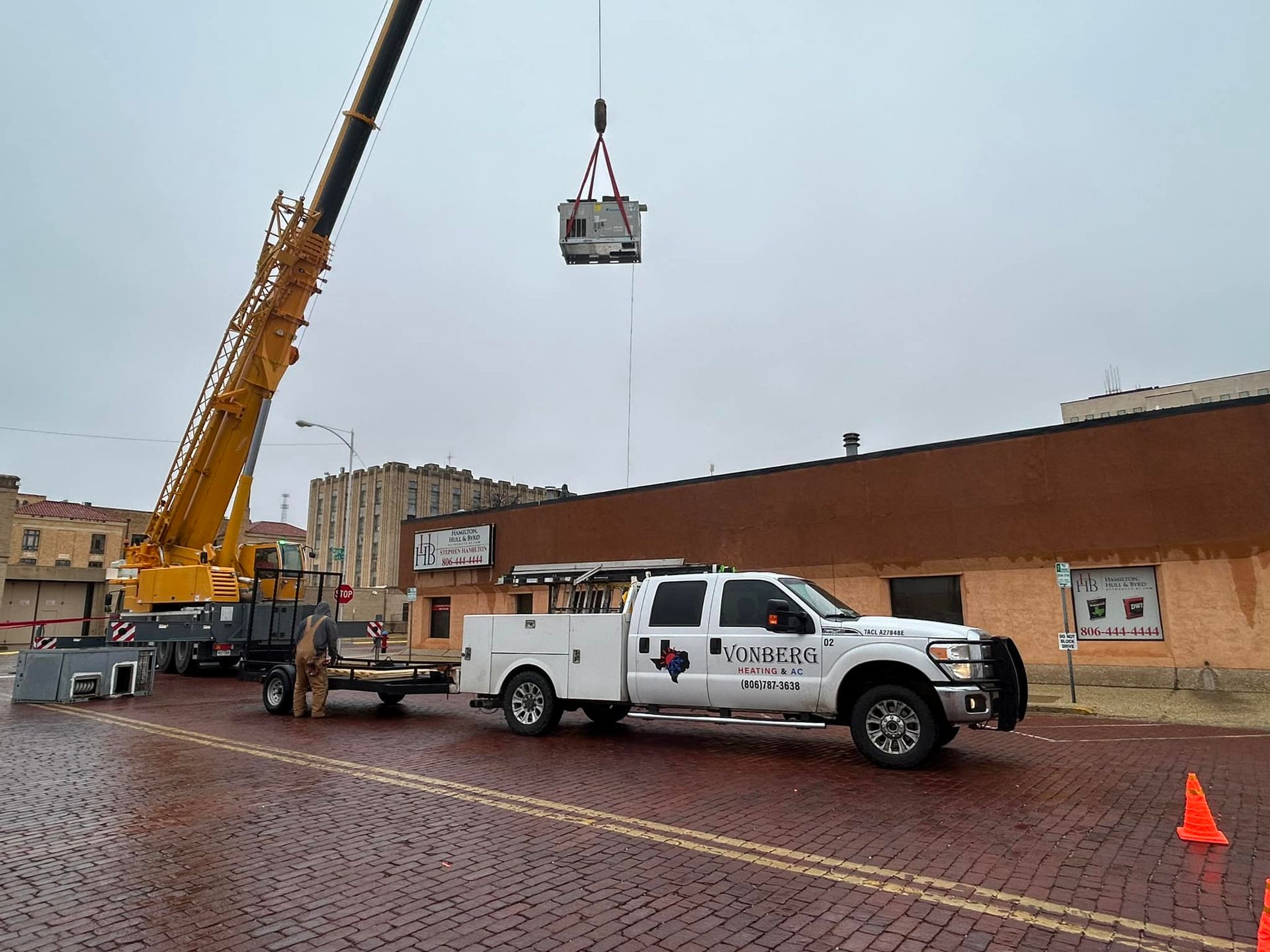 A white truck is being towed by a yellow crane.