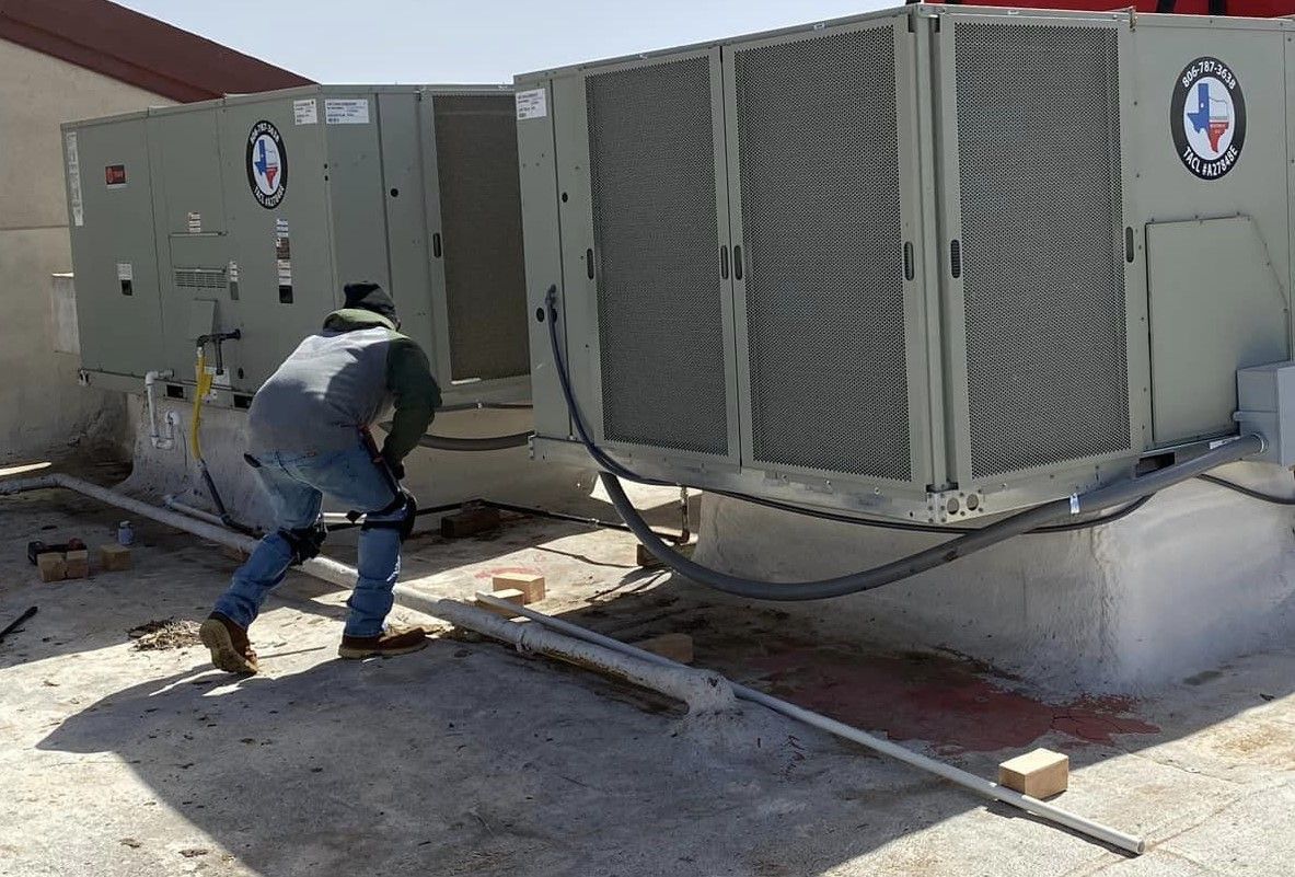 A man is working on a rooftop air conditioning system.