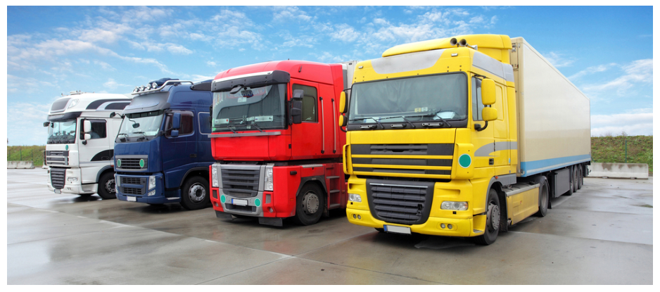 A row of semi trucks parked next to each other in a parking lot.