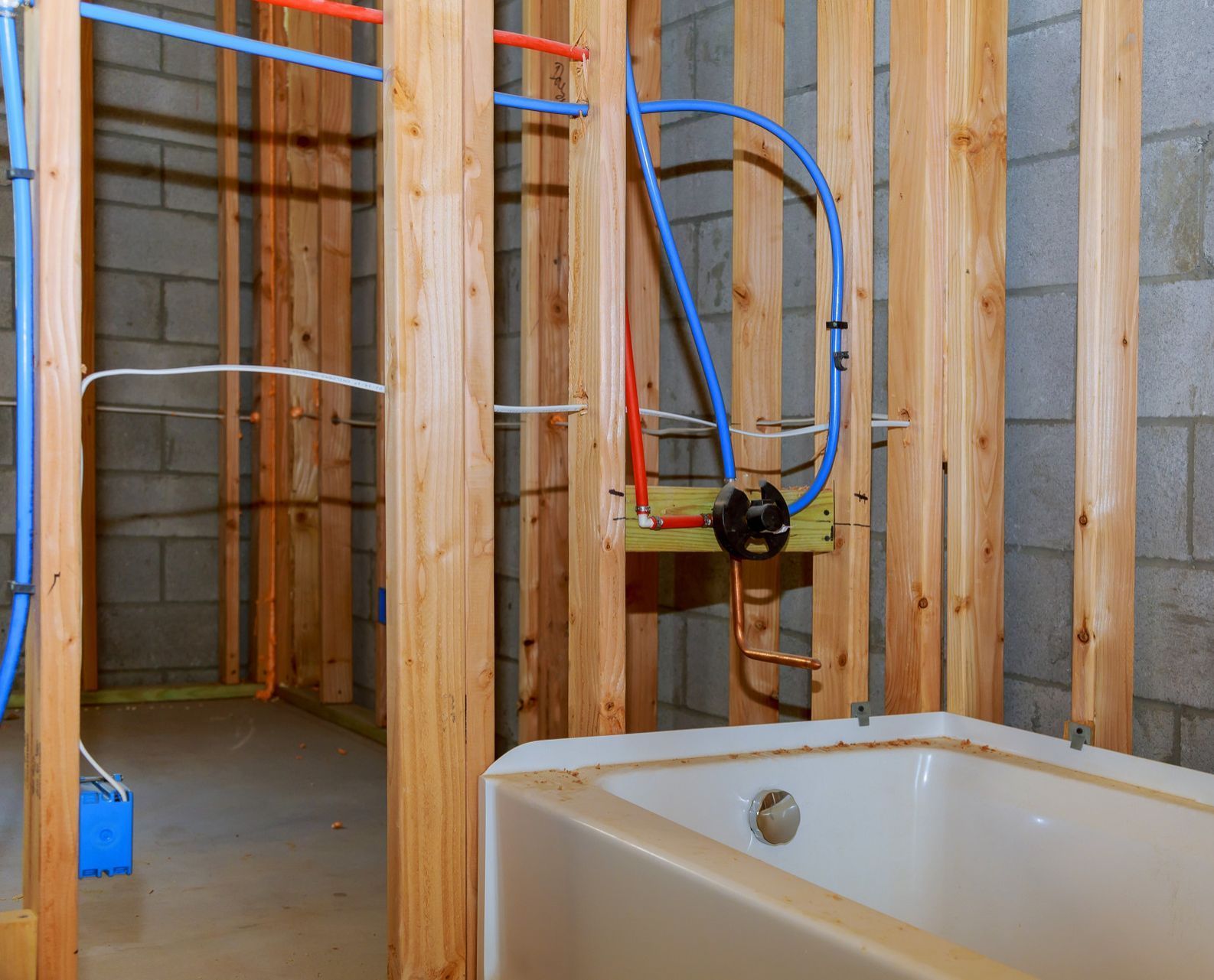 A bathroom under construction with a bathtub and pipes.