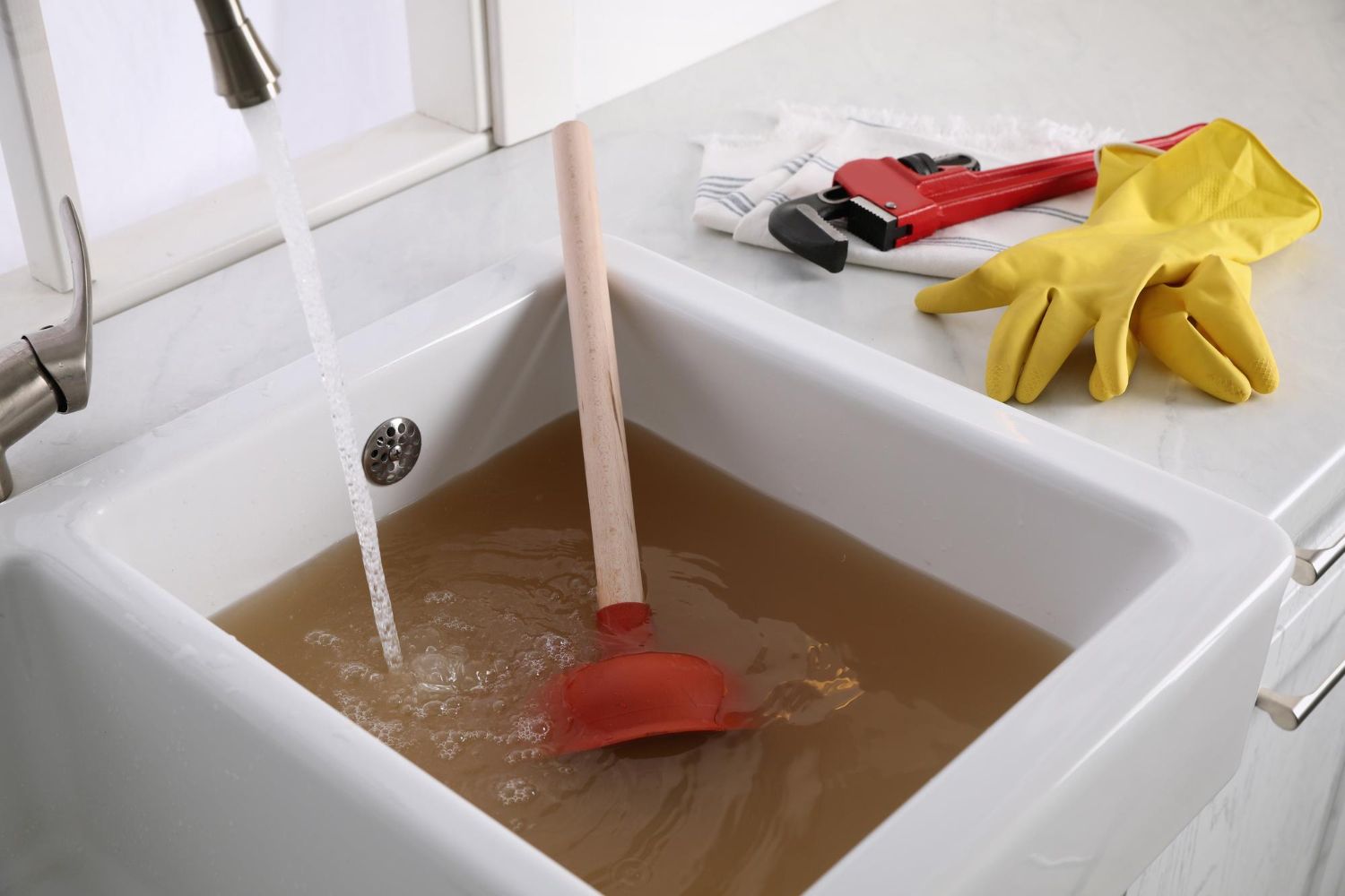 A sink filled with sewer water with a plunger in 